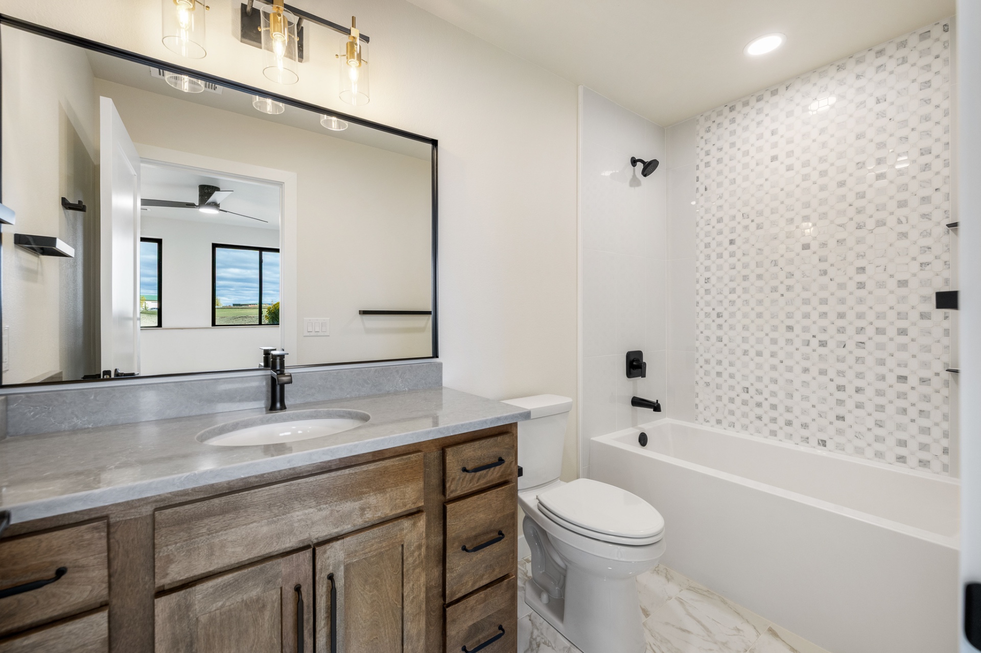 Guest bath with mosaic tile tub surround, stained vanity and black fixtures