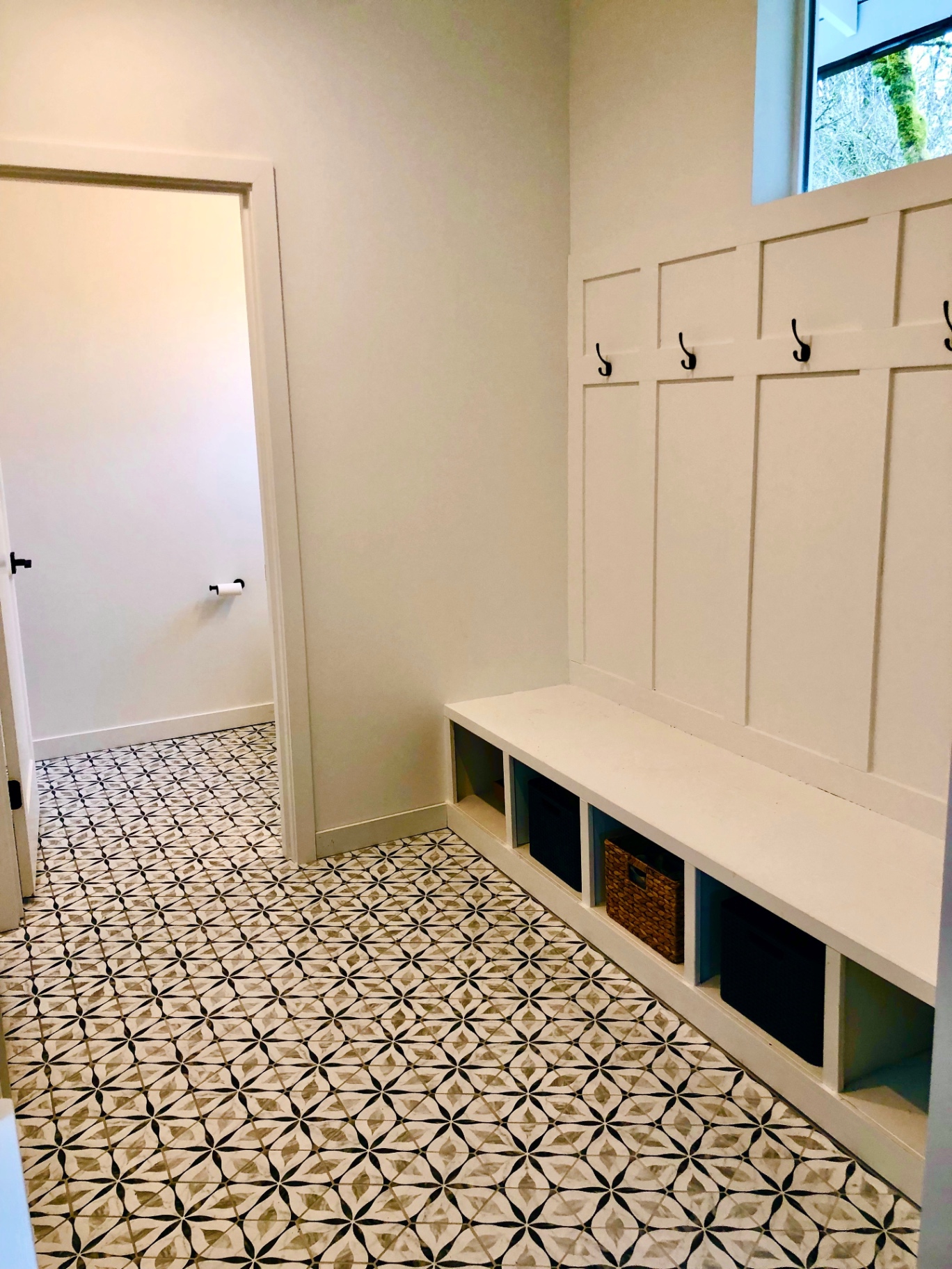 Custom mudroom with white built-in bench, hook wall and patterned cement tile floor