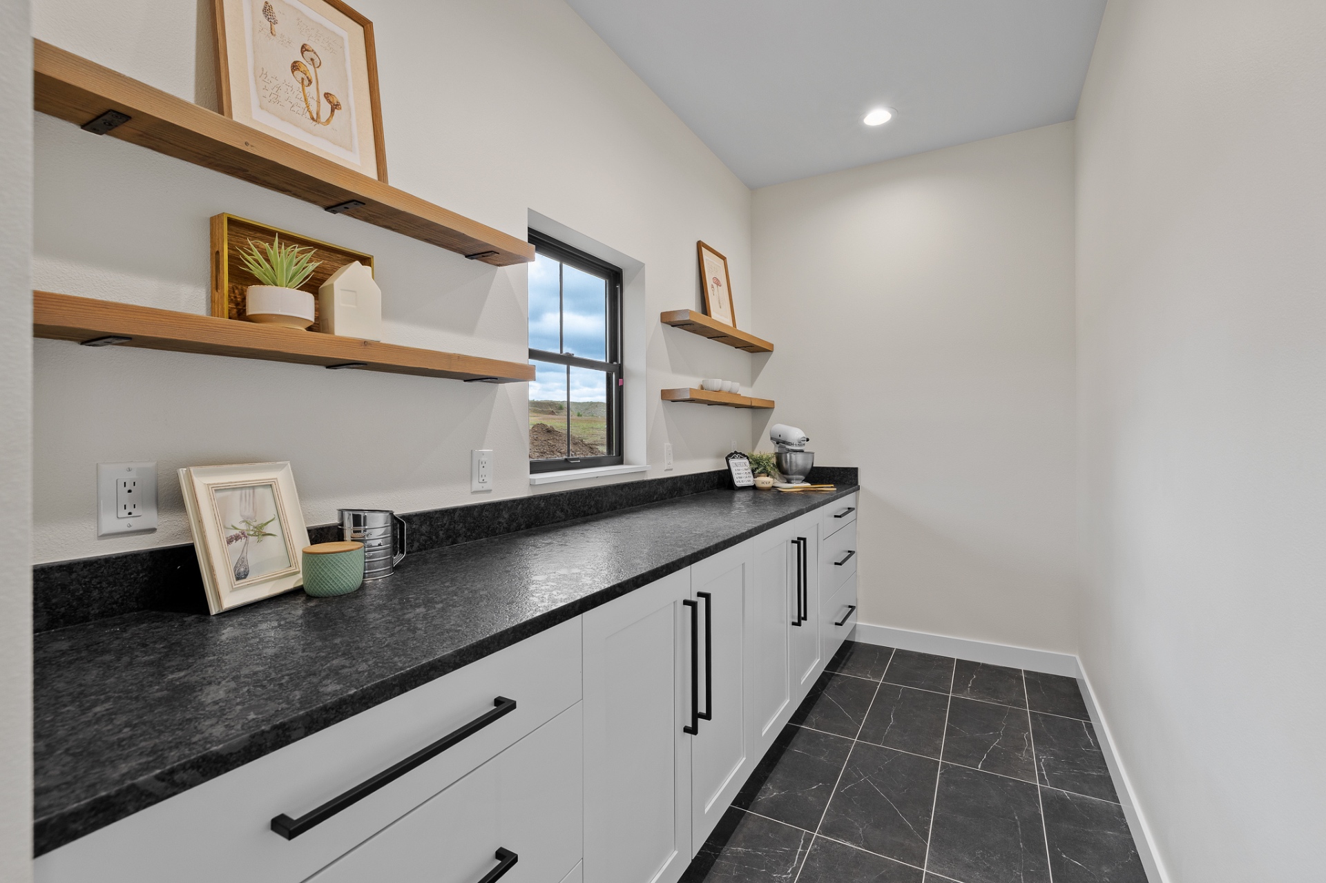 Butler's pantry with painted cabinetry, black counters and floating timber shelves
