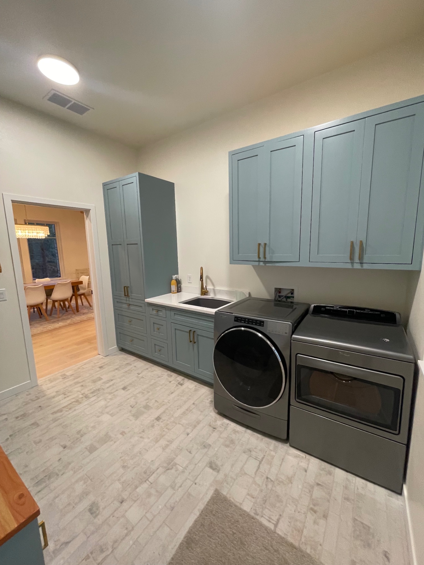 Custom laundry room with teal shaker cabinetry, quartz counters and brass hardware