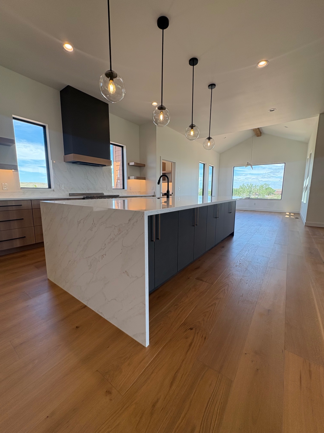 Vaulted kitchen with quartz waterfall island and charcoal cabinetry