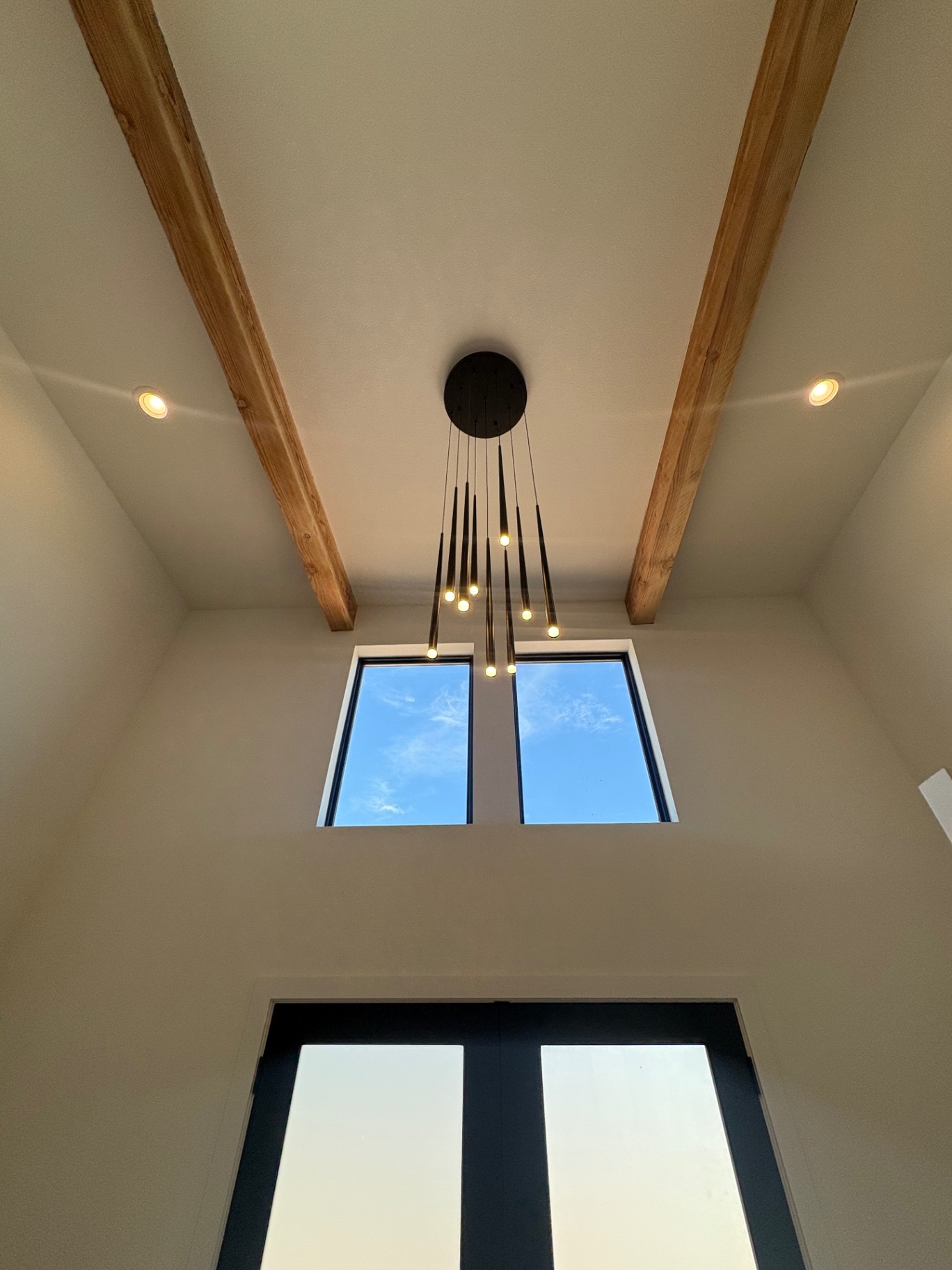 Entry with exposed timber beams and a modern chandelier in a Newhouse Builds custom home