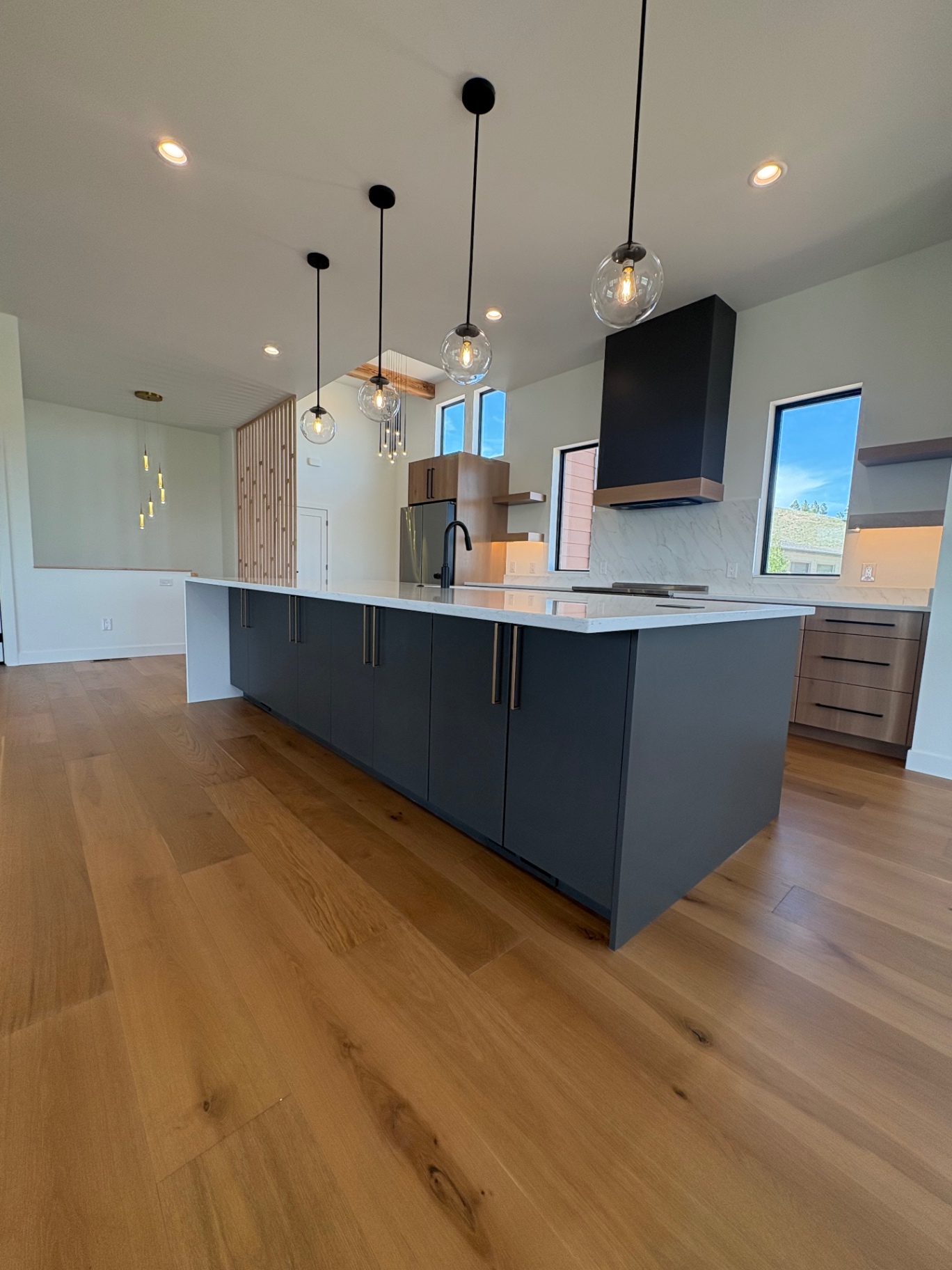 Custom kitchen with navy island, white oak cabinetry and glass globe pendants