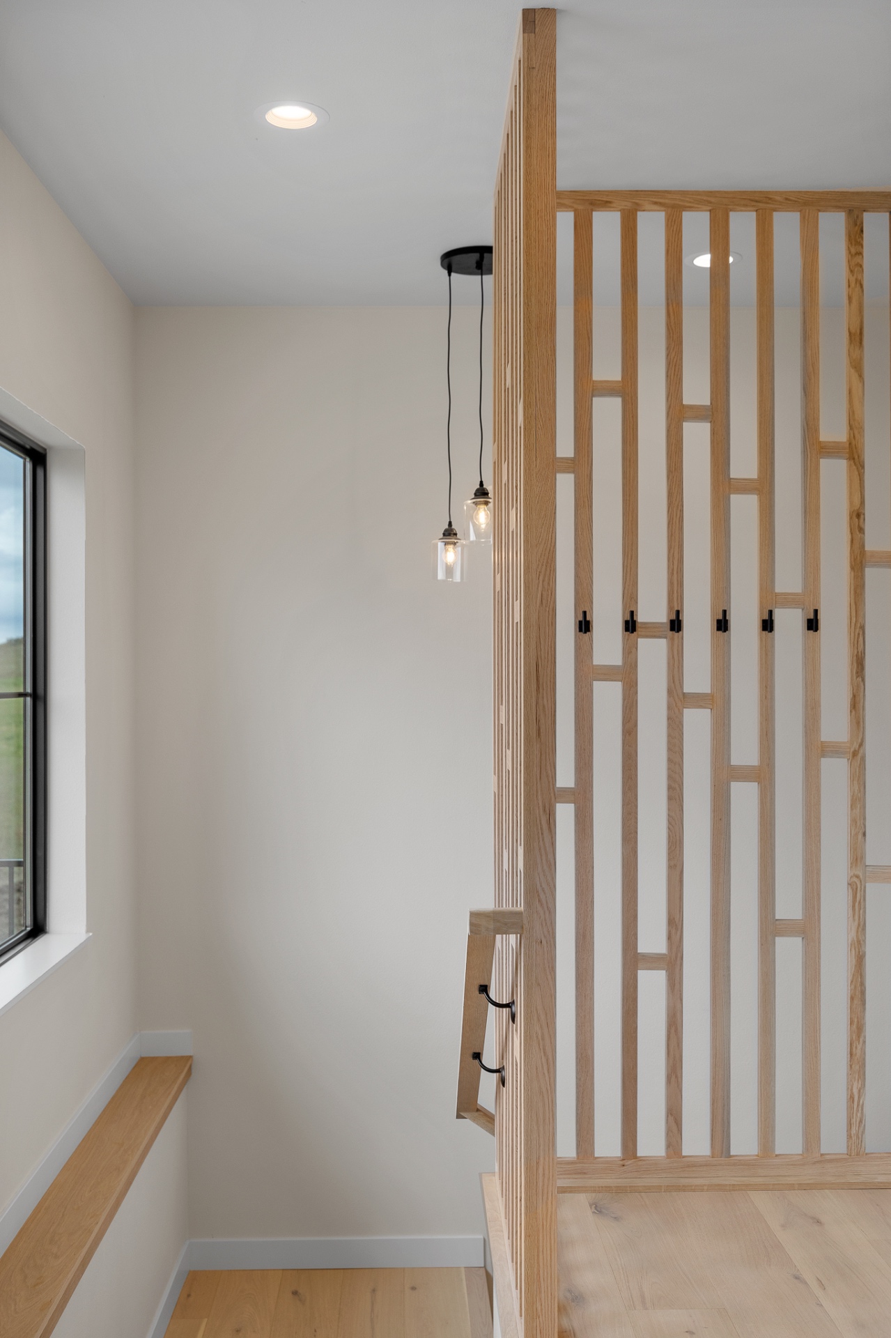 Entry drop zone with white oak slat screen, coat hooks and floating bench