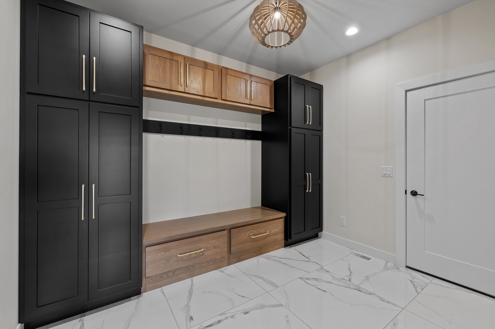 Custom mudroom cabinetry with matte black storage, oak drawers and a built-in bench