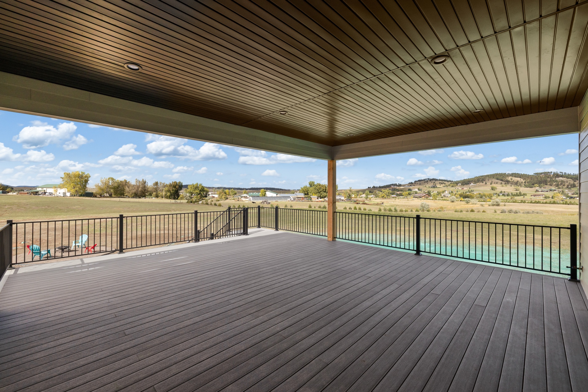 Covered rear deck with stained wood ceiling and prairie views