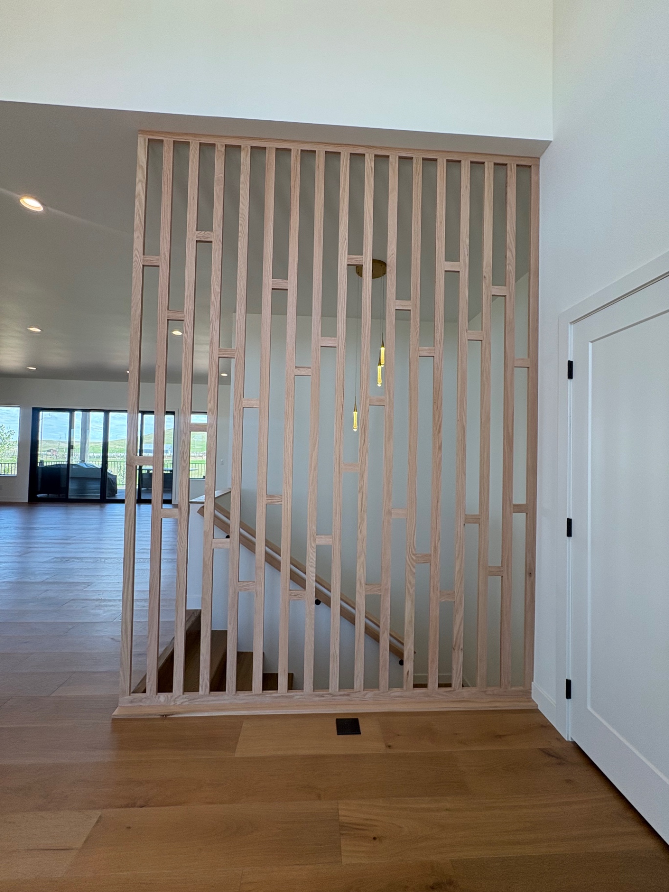 Custom white oak slat screen shielding the stairwell in a two-story great room