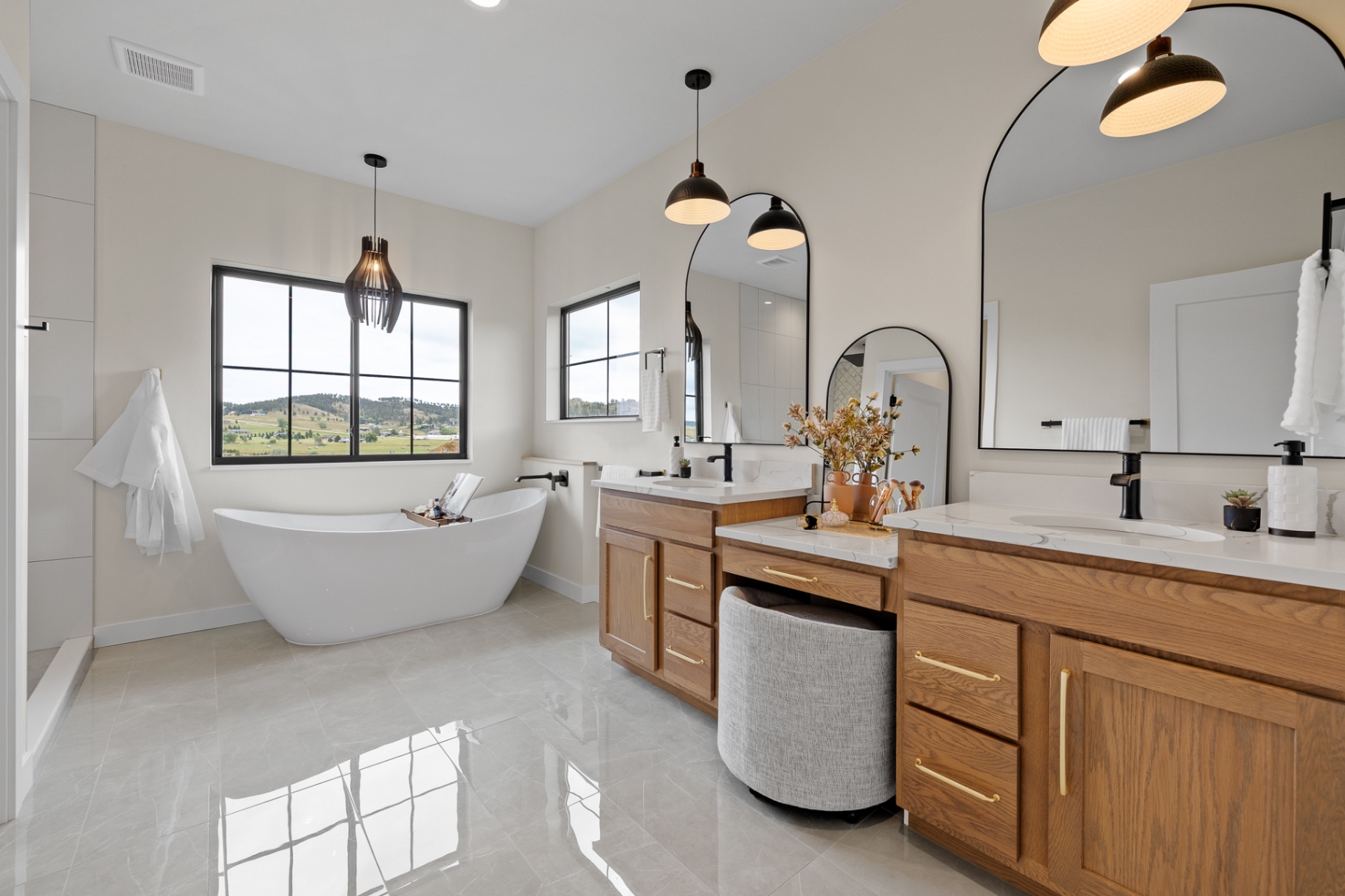 Primary bath with dual stained oak vanities and freestanding tub