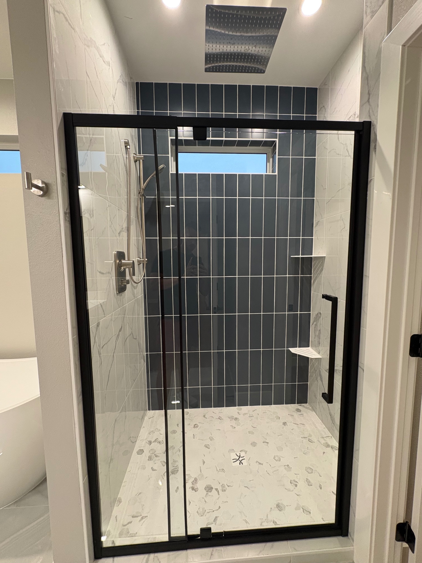 Walk-in shower with charcoal accent tile, marble-look walls and black-framed glass