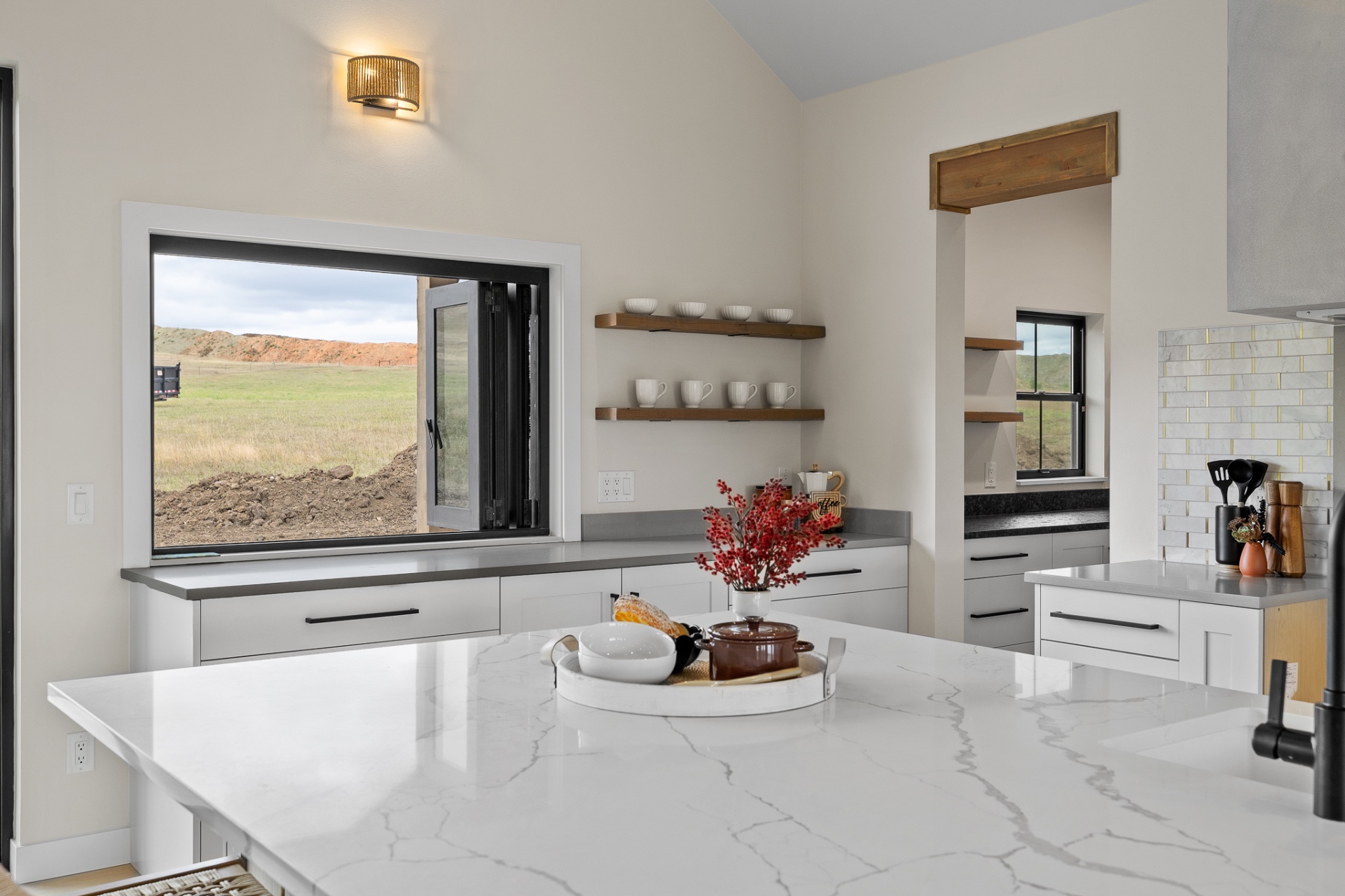 Kitchen island in veined quartz with floating wood shelves and marble backsplash