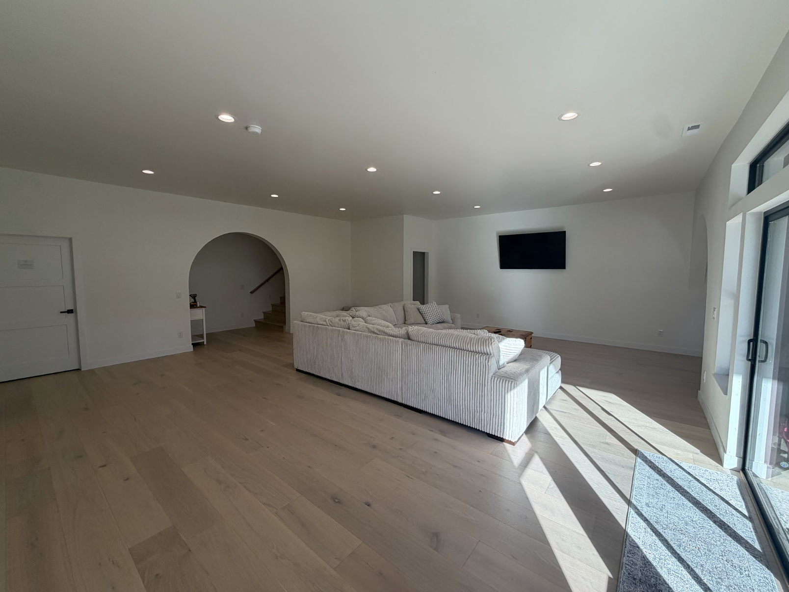 Great room with a striped sectional sofa, arched opening to the stair, recessed lighting and doors to the patio