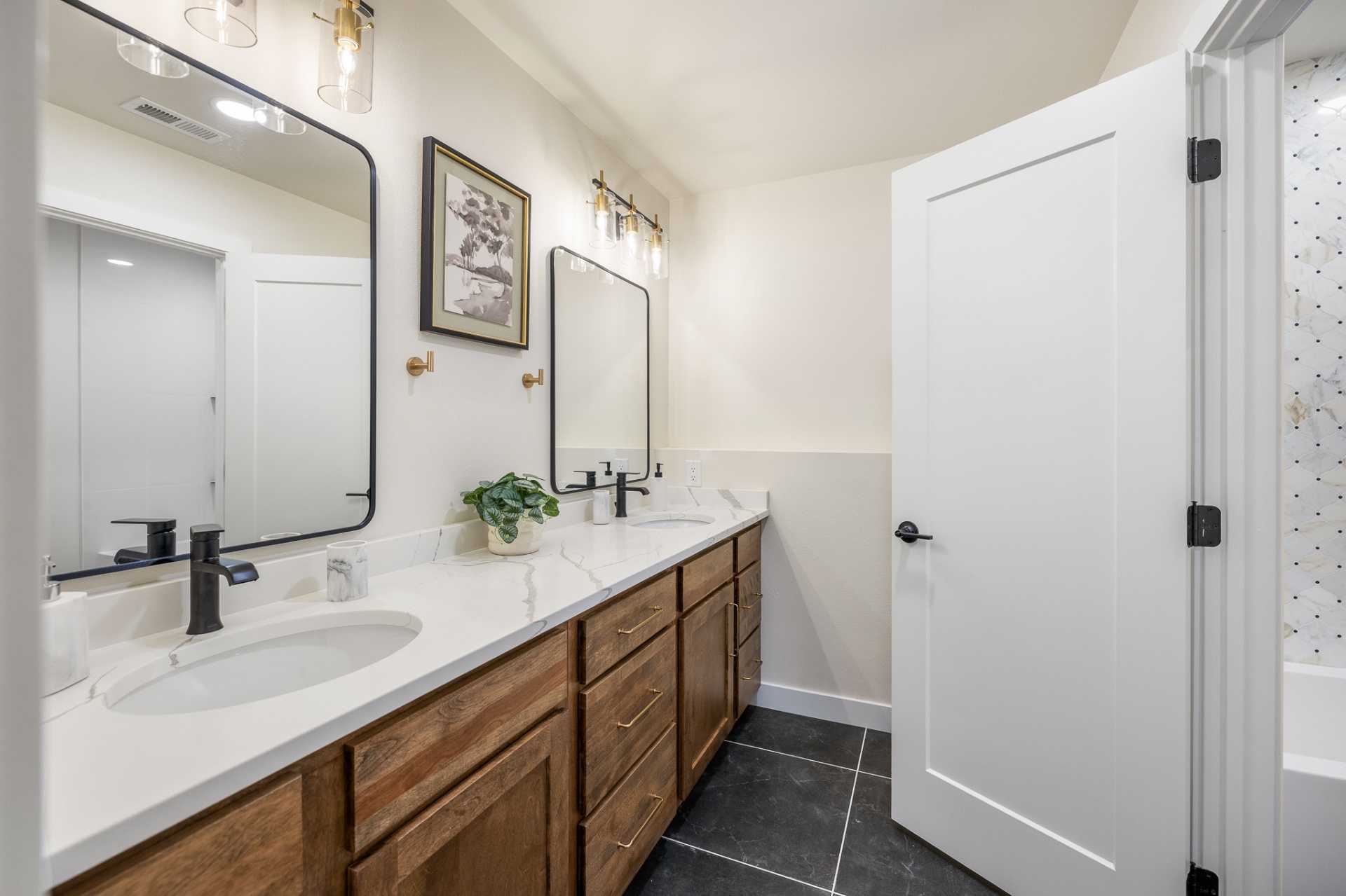 Guest bath with double stained wood vanity, quartz top and black framed mirrors
