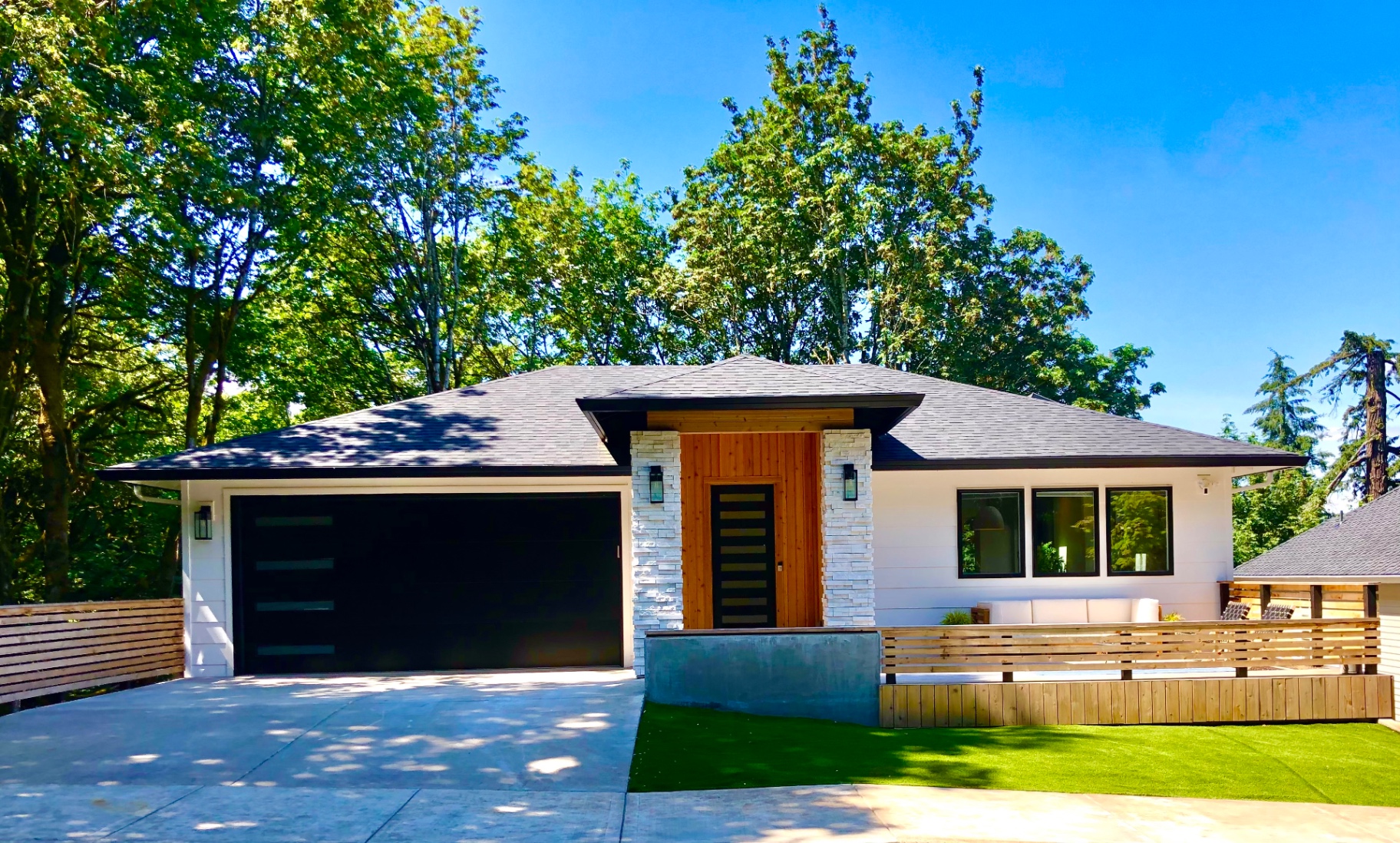White prairie-style custom home with low hipped roof, stacked stone entry columns and cedar accents