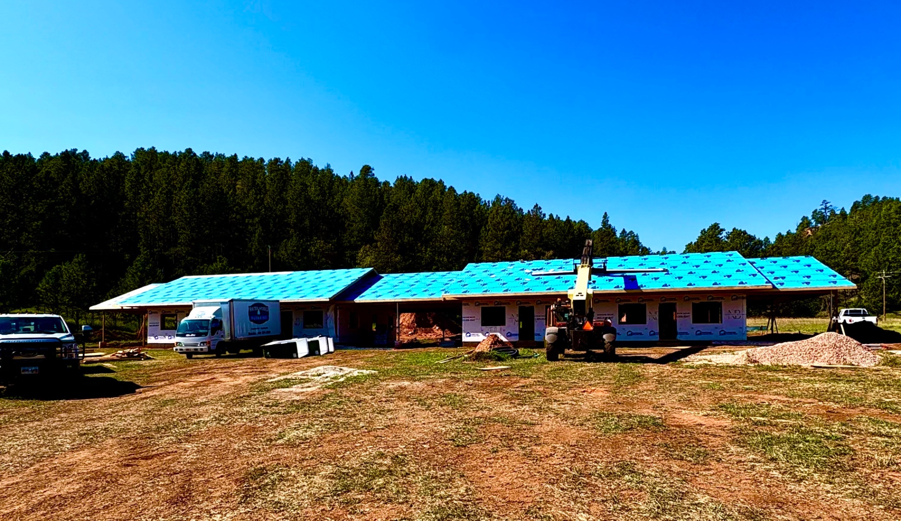 Custom home under construction with completed roof sheathing and house wrap