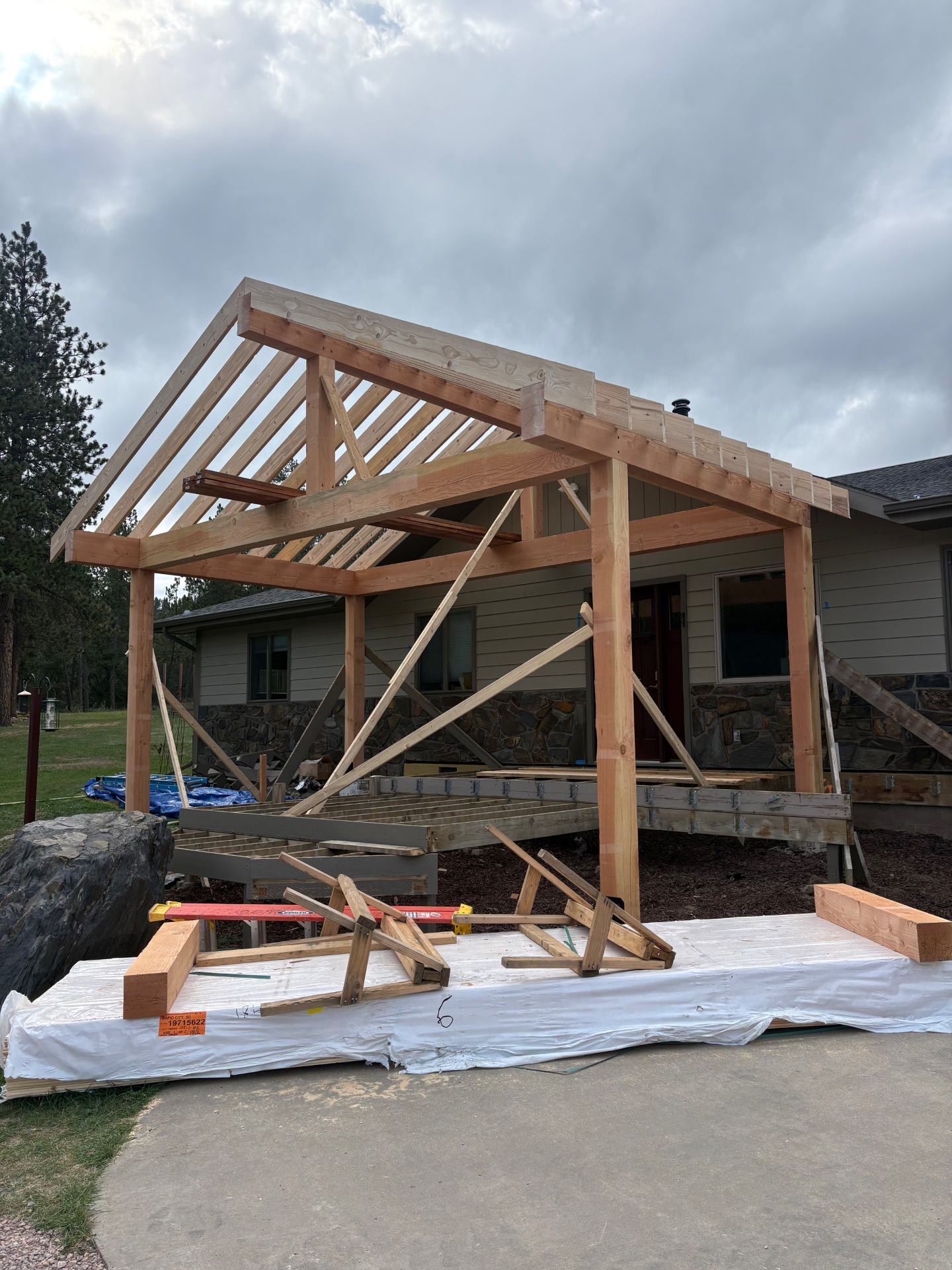 Timber-framed covered porch addition under construction on an existing home