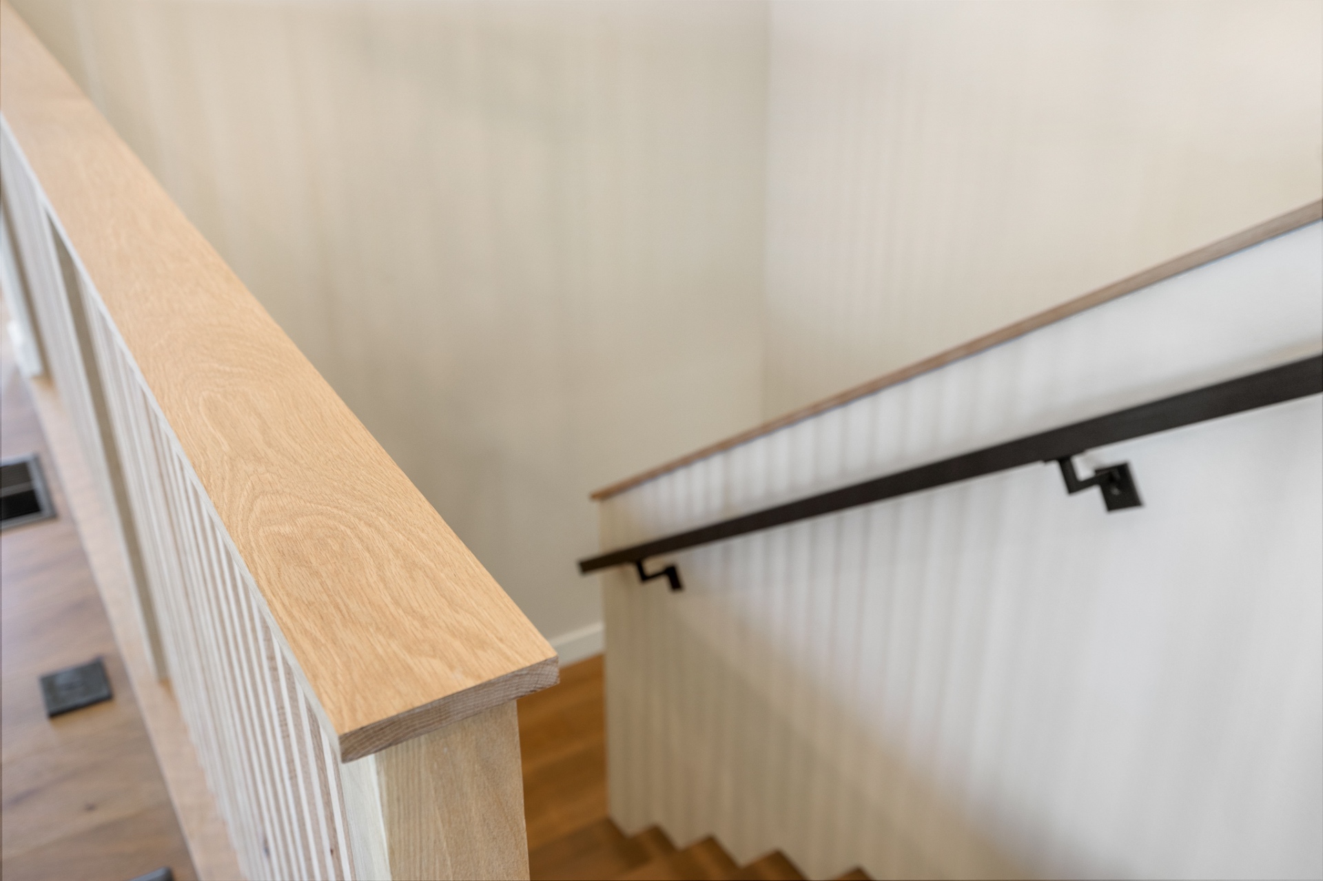 White oak stair rail cap and slat detail with black metal handrail