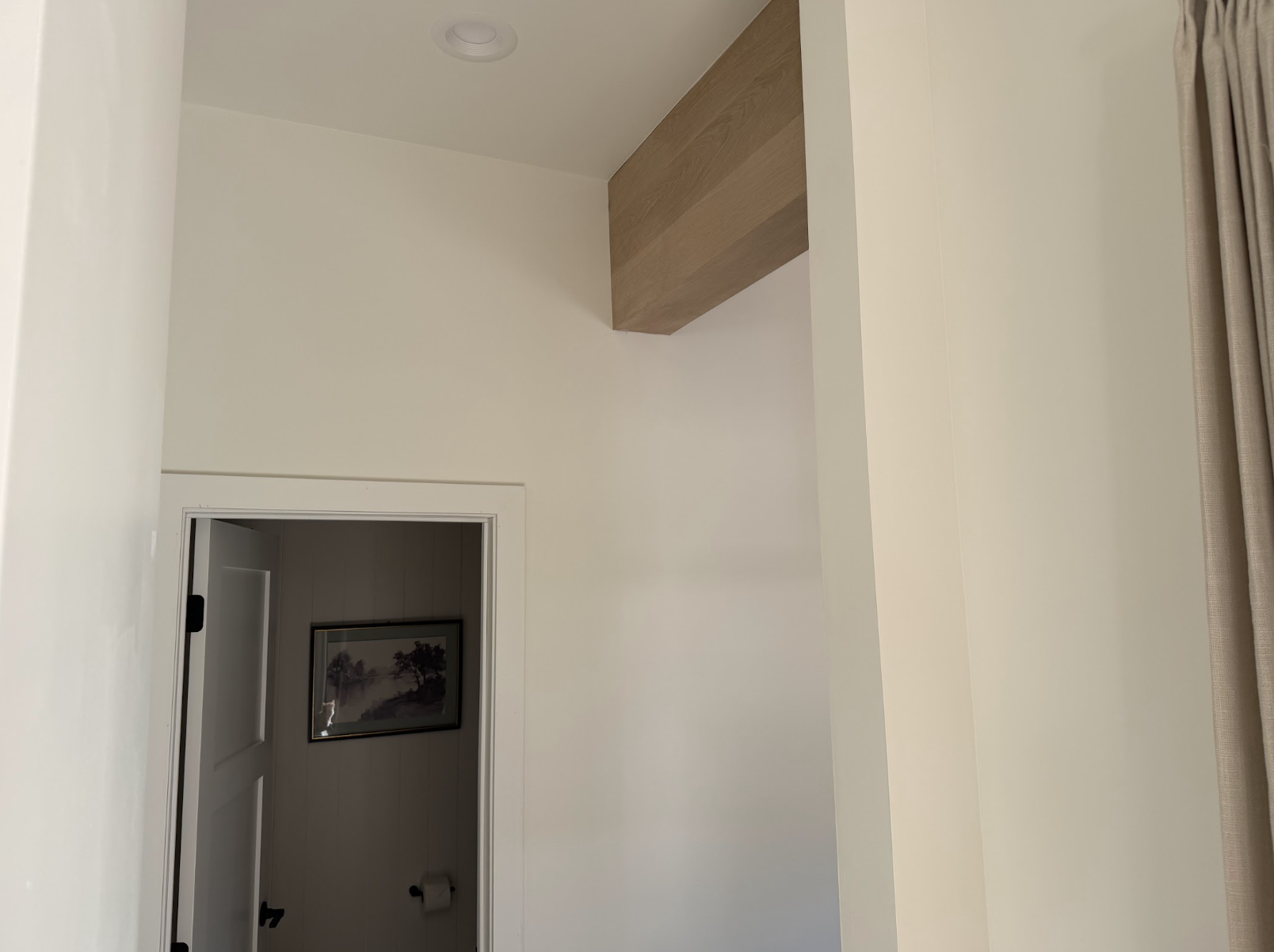Tall hallway detail with a white oak ceiling accent above the powder bathroom entry