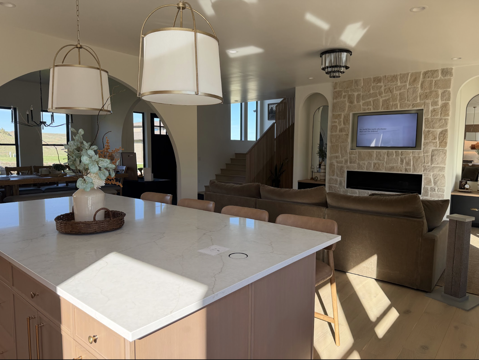 Kitchen island overlooking the great room, stone fireplace, arched openings and oak stair railing