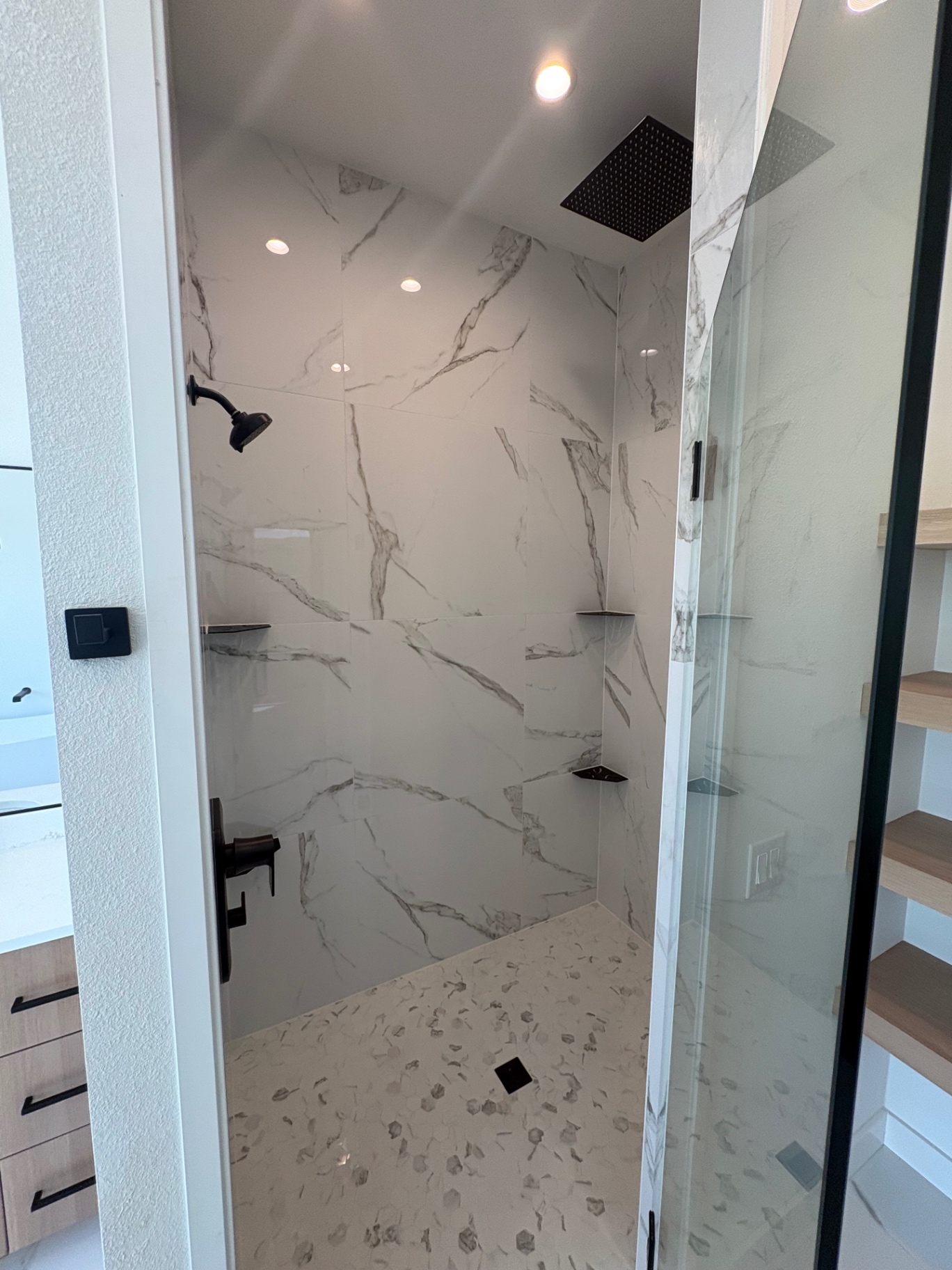 Walk-in shower with large-format marble-look porcelain, rain head and hex mosaic floor