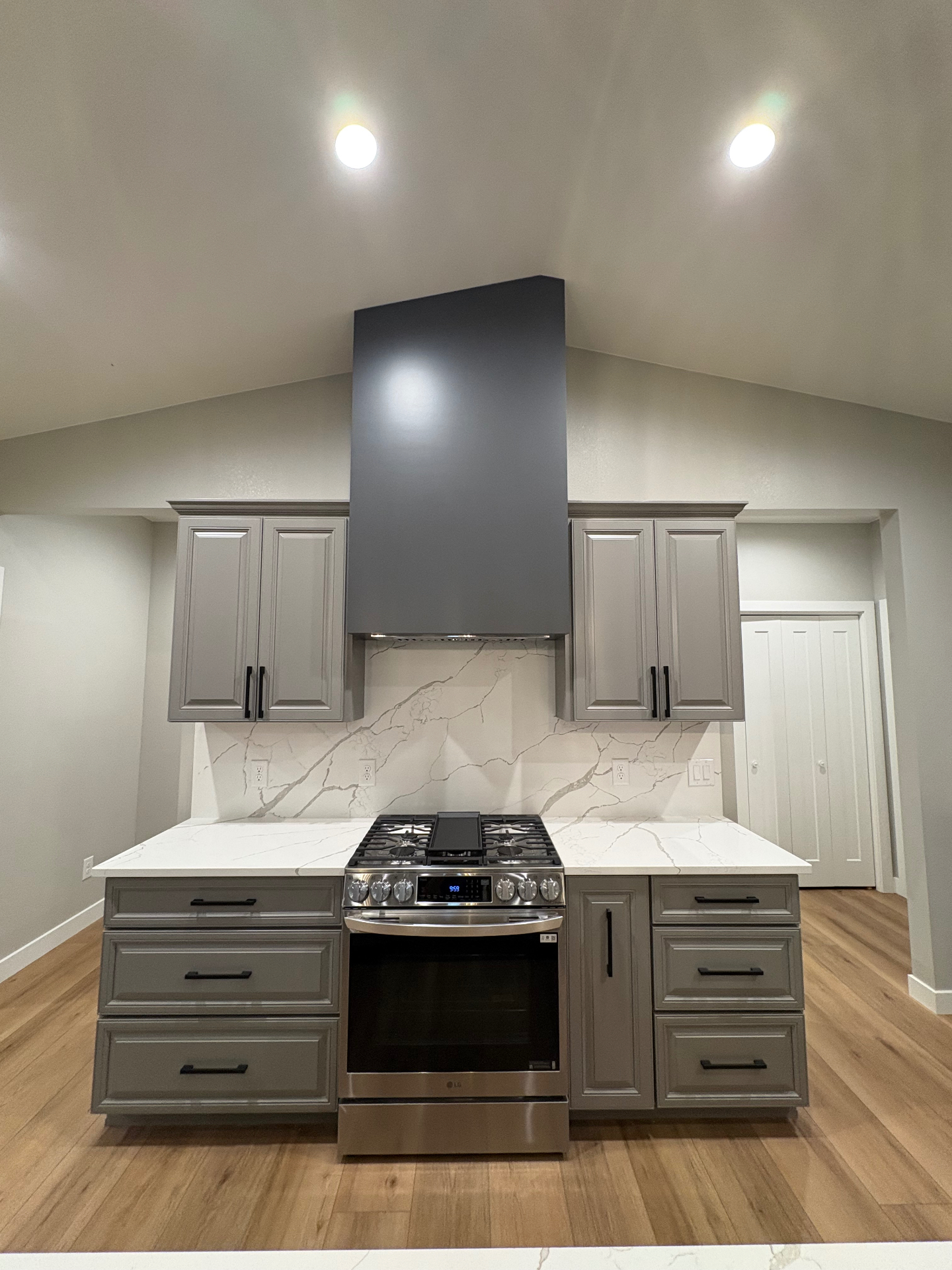 Symmetrical grey cabinet range wall with quartz backsplash and charcoal hood