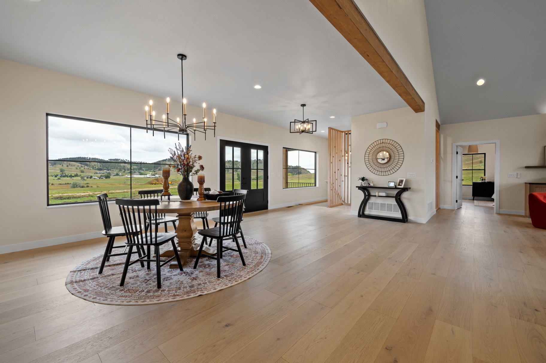 Open great room and dining area with vaulted ceiling, timber beam and Black Hills views