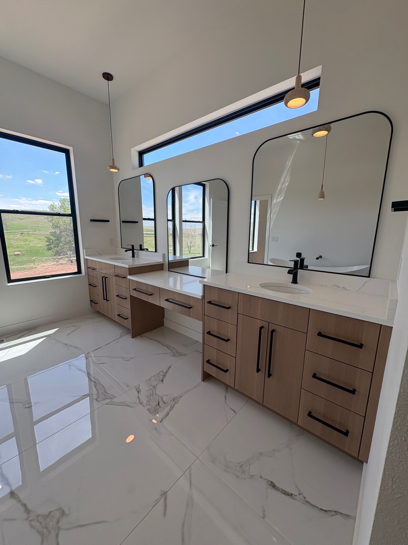 Twin white oak vanities with quartz tops and arched black mirrors