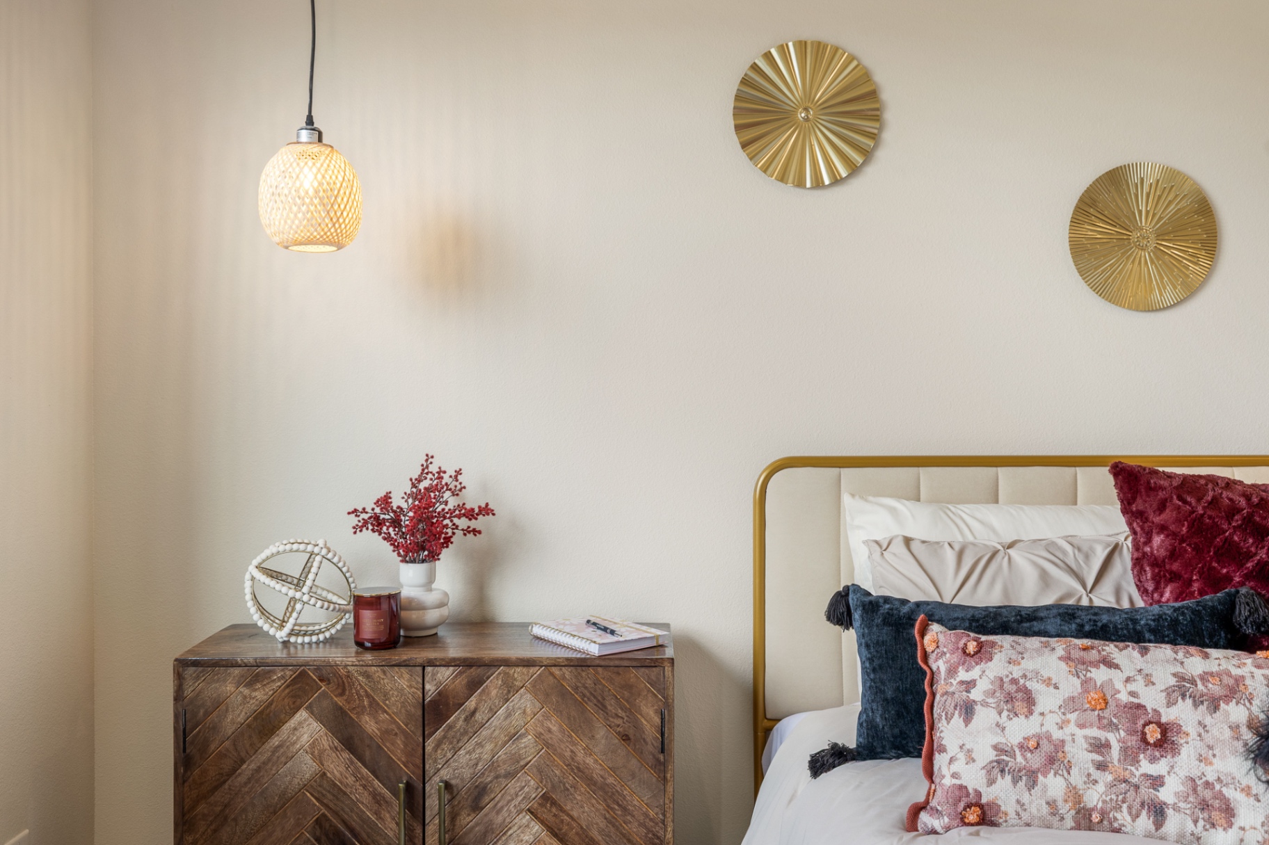 Bedroom with herringbone wood nightstand, brass accents and warm neutral walls
